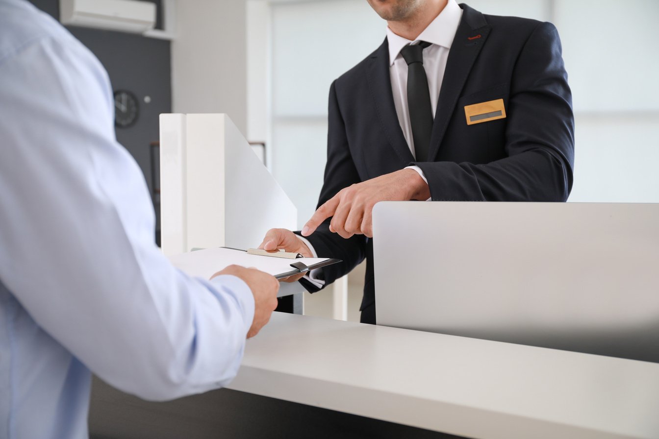 Male Receptionist Working with Visitor in Office